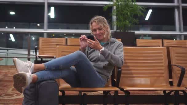 Μια γυναίκα στο αεροδρόμιο χρησιμοποιεί ένα smartphone στην αίθουσα αναμονής — Αρχείο Βίντεο