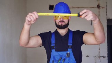 Erkek müteahhit inşaat bandıyla ölçer. Erkek müteahhit portresi