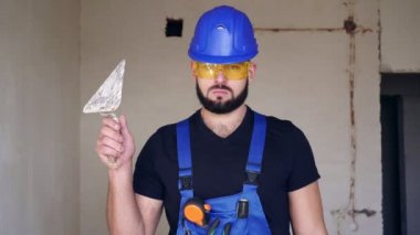 İnşaat alanında sakallı, ciddi bir erkek sıva ustasının portresi.