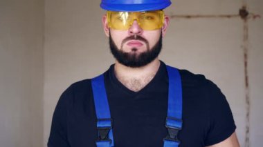 Ciddi bir erkek tesisatçının portresi. Tesisat anahtarı olan bir inşaat işçisi.