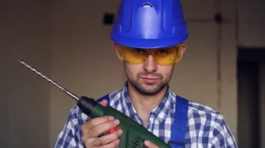 Elektrikli çekiç matkabı olan ciddi bir erkek müteahhit. İnşaat alanındaki bir inşaatçının portresi