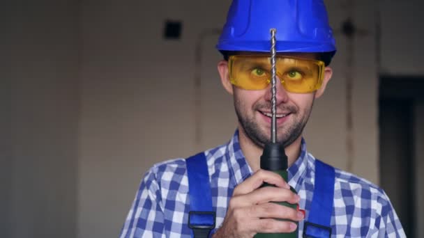 Ritratto di un buffo costruttore maschio pazzo. Allegro lavoratore maschile con un trapano a martelli — Video Stock