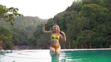 Açık havuzda mayo giymiş güzel, seksi bir kadın.