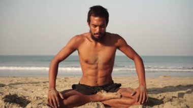 Lotus pozisyonundaki bir adam denizde yoga yapar.