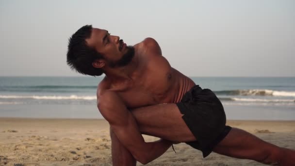 Ένας άντρας κάνει γιόγκα σε μια άδεια παραλία. Ένας άντρας κάνει γιόγκα στο φόντο της θάλασσας. — Αρχείο Βίντεο