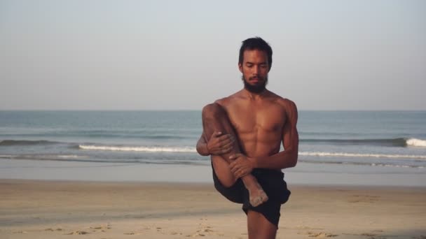 Мужчина практикует йогу в природе. Азиатский мужчина делает упражнения и йогу на пляже — стоковое видео