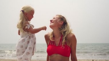 Sahilde bebeği olan genç bir anne denizin arka planında.