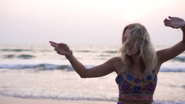 Молодая женщина танцует на пляже в традиционной восточной одежде — стоковое видео