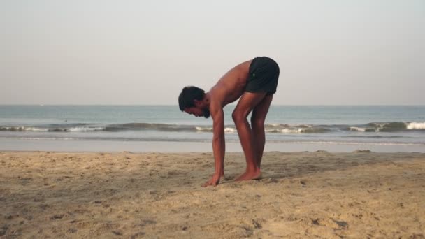Чоловік практикує йогу на пляжі. Чоловік практикує йогу на тлі моря — стокове відео