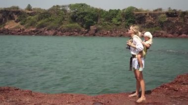 Vahşi deniz sahilinde çocuklu bir kadın turist. Bir kadın küçük bir çocukla seyahat eder.