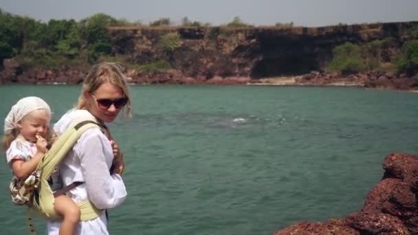 Una donna viaggia con un bambino piccolo. Donna turista con un bambino su una spiaggia di mare selvaggio — Video Stock