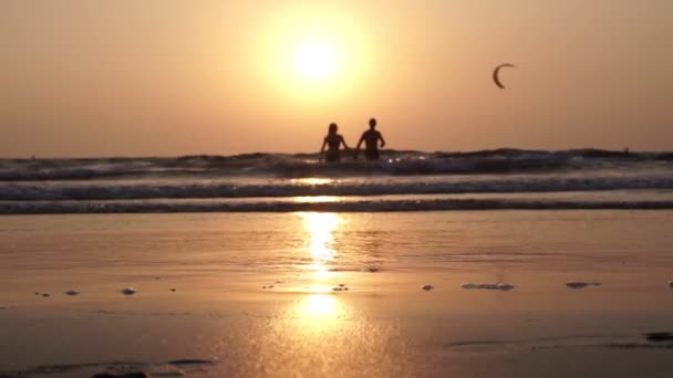 한 젊은 부부가 석양을 배경으로 바다에서 나옵니다. 아름다운 열 대의 배경. — 비디오