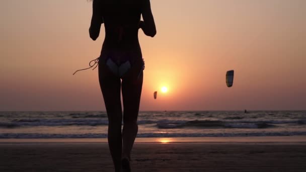 Silueta de una mujer caminando a lo largo de la playa sobre un fondo de puesta de sol — Vídeo de stock