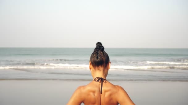Жінка практикує йогу на пляжі. Дівчина займається фізичними вправами на тлі моря — стокове відео