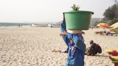 Arambol, Hindistan - Şubat 2020. Bir kadın satıcı kafasında meyve olan bir sepet taşıyor.