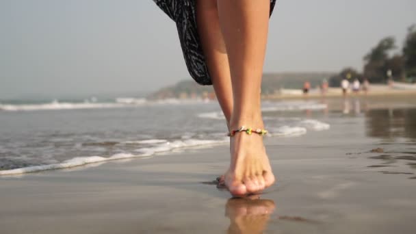 Eine Frau geht auf dem Wasser an einem Sandstrand. Füße spazieren auf dem Meer. — Stockvideo
