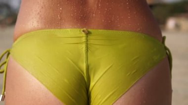 Plajda ıslak bikinili seksi bir kadın mayo giyiyor. Sahilde bikinili bir kız.