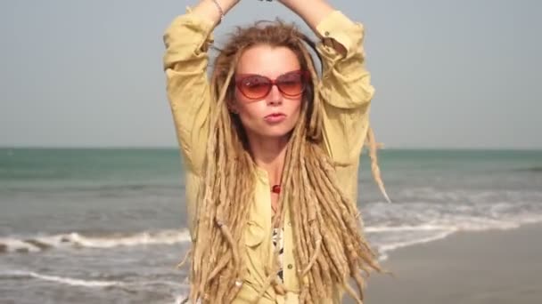 Porträtt av en hipsterflicka med dreadlocks på stranden. Glada hippie kvinna — Stockvideo