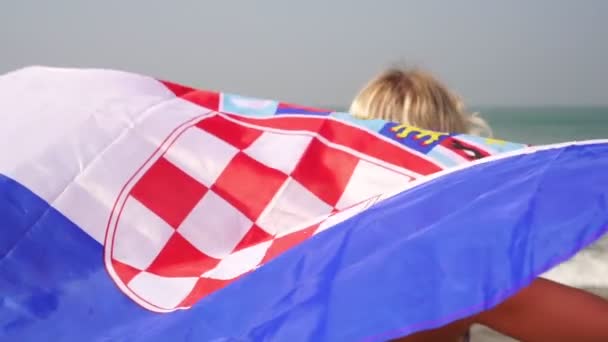 Fiatal nő horvát zászlóval a tengerparton, lassított felvétel. Turizmus Horvátországban — Stock videók