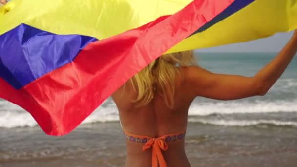 Γυναίκα με σημαία Κολομβίας στην παραλία. Κορίτσι με μπικίνι με κολομβιανή σημαία στη θάλασσα — Αρχείο Βίντεο