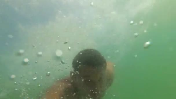 Muž plave pod vodou v moři. Muž se ponoří do moře a plave pod vodou — Stock video