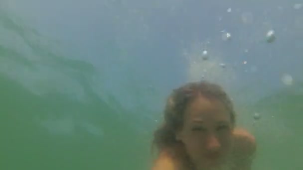 一个女人在水下游泳。那女孩潜入海里,在水里游泳. — 图库视频影像