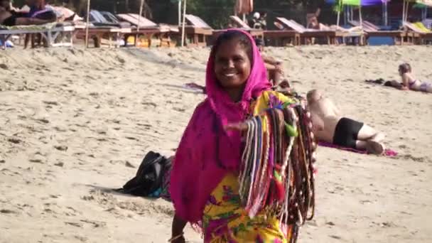 Arambol, India - januari 2020. Een Indiase vrouw verkoper loopt langs het strand in Goa. — Stockvideo