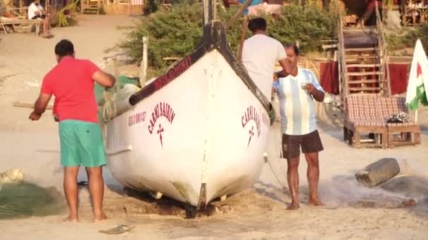 Arambol, Indien - Februar 2020. Strand von Goa, indische Fischer in der Nähe des Bootes. — Stockvideo