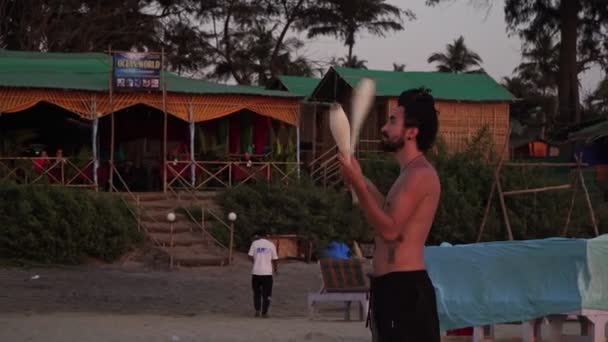 Arambol, Indien - februari 2020. Manlig konstnär jonglör med klubbar på en strand i Asien. — Stockvideo