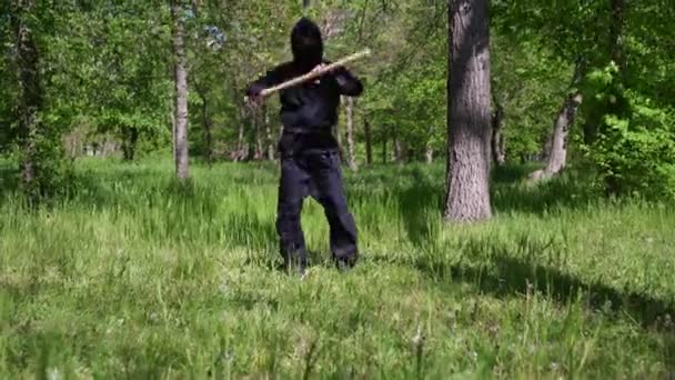 Japonský ninja trénuje s dřevěnou holí s obuškem. Maskovaný ninja — Stock video