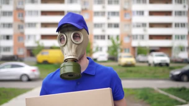 Courier deliveryman με μάσκα αερίου ή αναπνευστήρα μεταφέρει το δέμα — Αρχείο Βίντεο