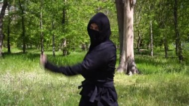 Siyah cüppeli Japon ninja ormanda eğitim görüyor. Maskeli bir ninja portresi.