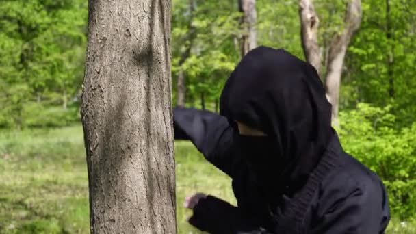 Ninja training in nature. Japanese ninja fulfills blows on a tree. — Stock Video