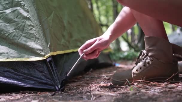 여자 관광객 이 텐트를 만든다. 한 관광객 이 천막에 쐐기를 박는다 — 비디오
