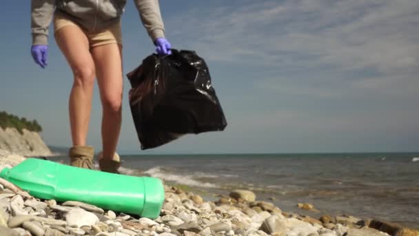 Чоловік чистить пляж сміття. Жінка збирає пластикові відходи на березі моря — стокове відео