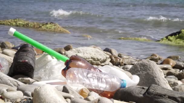 Botellas de plástico y basura en la playa sobre un fondo del mar. Contaminación del mar — Vídeos de Stock