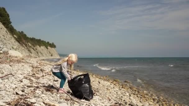 Дитина і жінка очищають морський пляж від сміття і пластикових пляшок — стокове відео