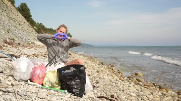 Ekologka žena s pytli odpadků a plastového odpadu na pozadí moře — Stock video