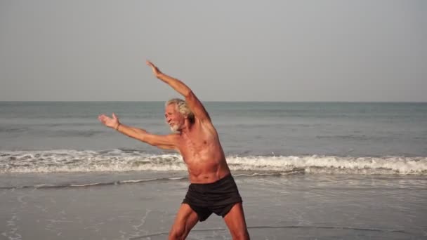 Дедушка тренируется на пляже. Пожилой мужчина, занимающийся спортом — стоковое видео