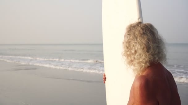 Volwassen man, grootvader met surfplank op de achtergrond van de zee — Stockvideo