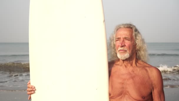 Yetişkin bir adamın portresi, büyükbaba, sahilde sörf tahtası olan yaşlı bir adam. — Stok video