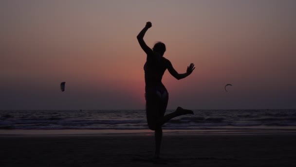 Egy nő jógázik naplementekor. Egy lány sziluettje, aki jógázik. — Stock videók