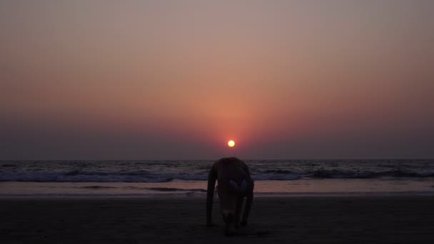 Inclinez-vous devant le soleil au coucher du soleil. Une femme pratique le yoga au coucher du soleil sur le fond de la mer — Video