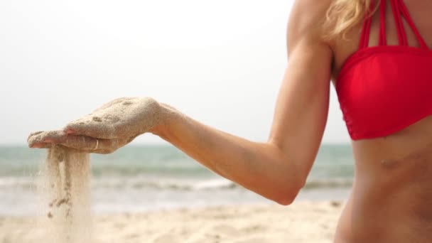 Zand valt en vloeit tussen de vingers van een persoon. Het begrip vergankelijkheid van tijd — Stockvideo