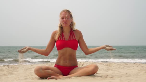 Eine Frau meditiert und macht Yoga am Strand vor dem Hintergrund des Meeres — Stockvideo