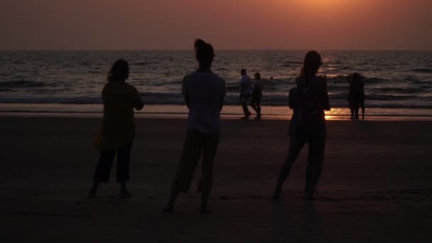 Arambol, Indien - Februar 2020. Eine Gruppe von Leuten macht Yoga am Strand bei Sonnenuntergang. Menschen machen Qigong-Übungen. — Stockvideo