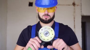 Açı öğütücüsü olan bir inşaatçının portresi. İnşaat alanında bir aletle çalışan