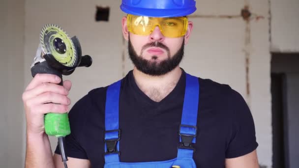男性のビルダーは角度グラインダーを持っています。工事現場における労働者の肖像 — ストック動画