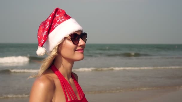 Портрет молодої жінки в капелюсі Санта - Клауса на тлі моря. — стокове відео