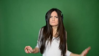 güzel çekici genç kız dans ve kulaklık müzik ile şarkı ve iyi konsept yeşil stüdyo arka planda izole hissediyorum